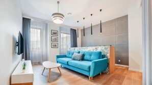 Ein modernes Wohnzimmer mit einem blauen Sofa, einem weißen Couchtisch und einem an der Wand montierten Fernseher.