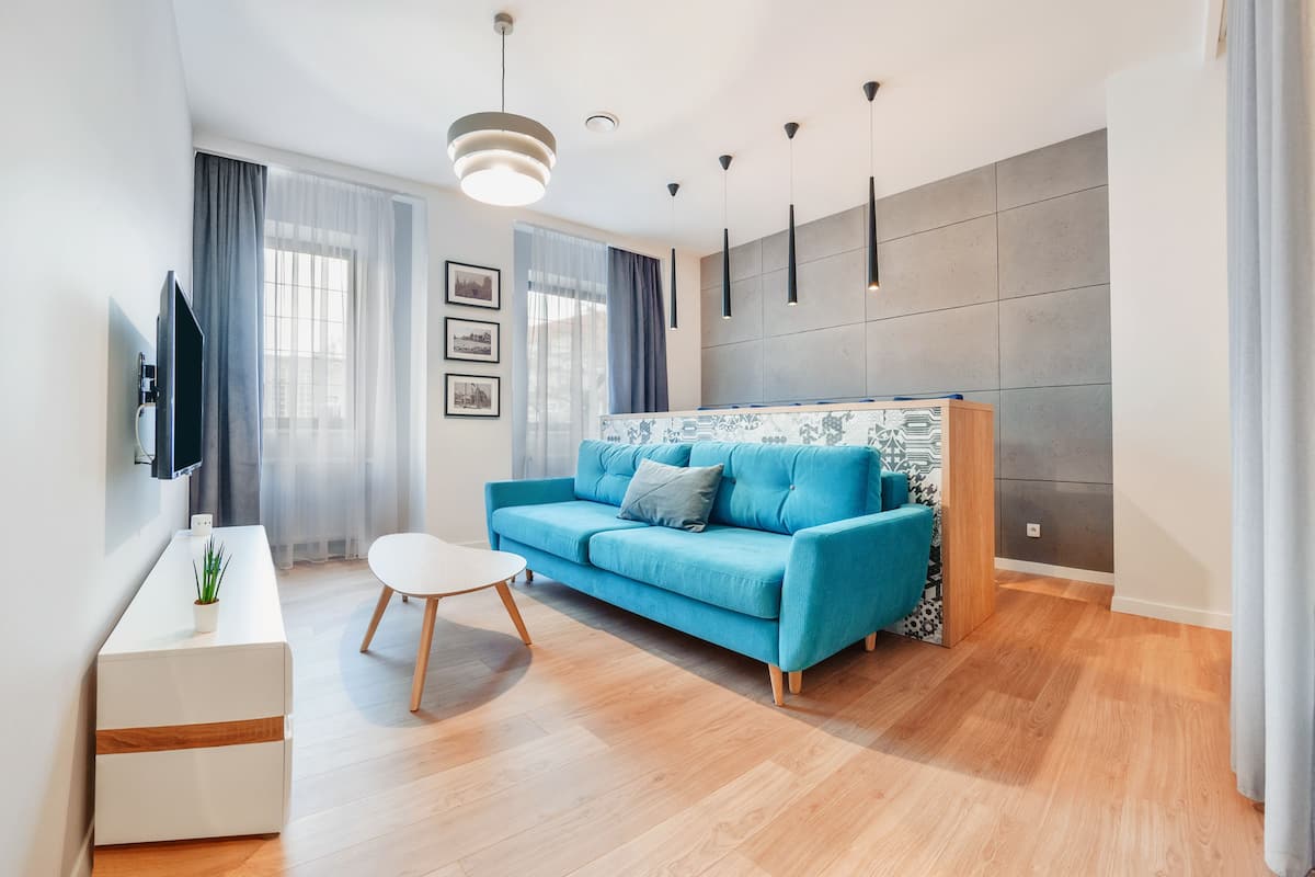 A modern living room with a blue sofa, a white coffee table, and a TV mounted on the wall.
