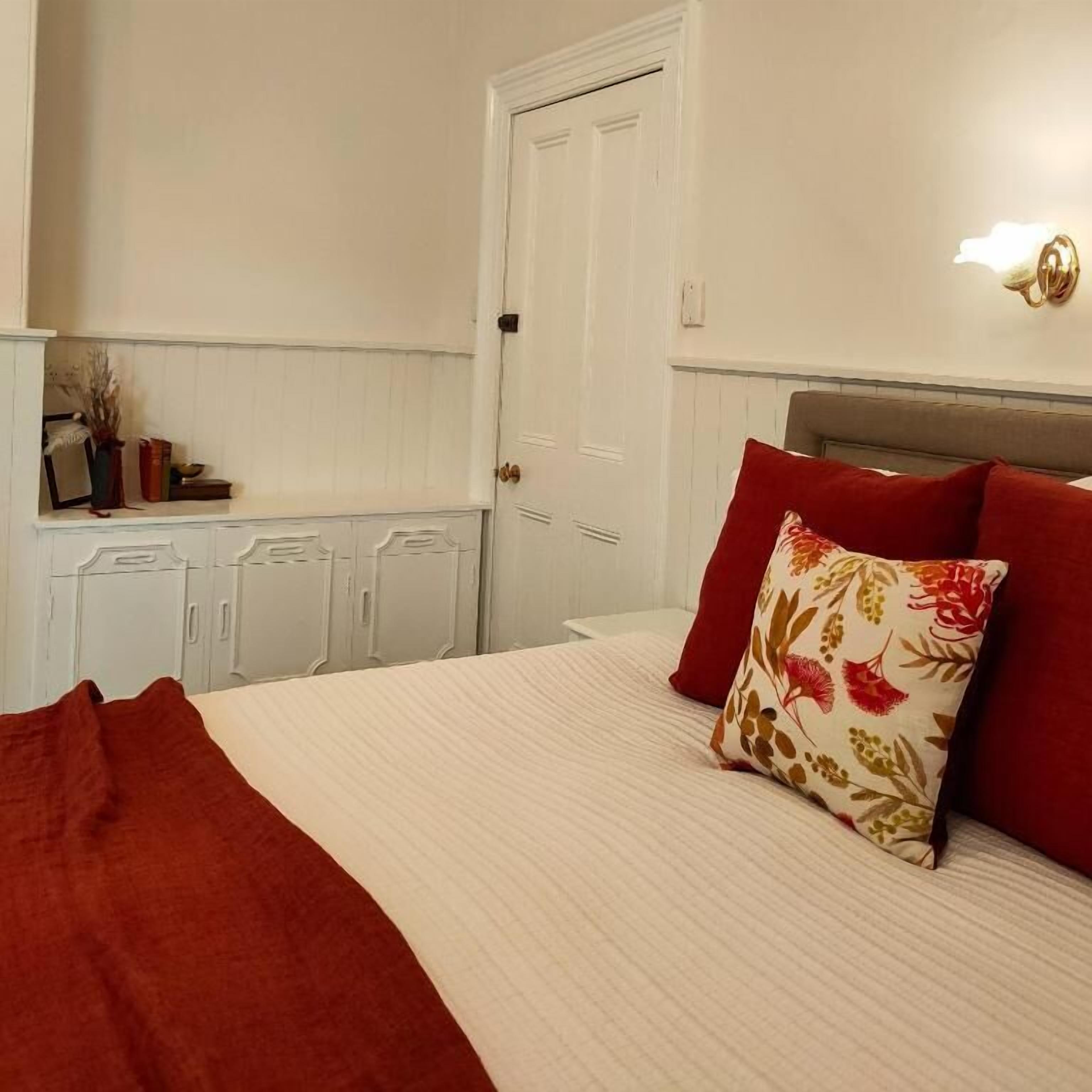 A bedroom with a bed, a nightstand, a dresser, and a door.