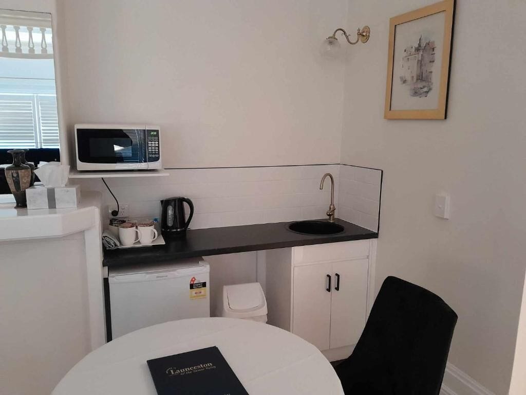 Een kleine keuken met een magnetron, koffiezetapparaat en spoelbak.
