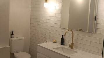 A bathroom with a white toilet, a sink with a gold faucet, and a mirror above the sink.