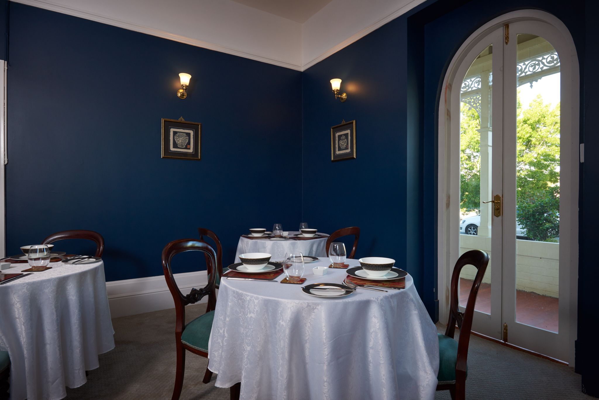 Un comedor con mesas redondas, sillas y vistas a través de un ventanal.