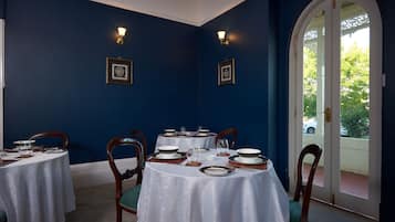 Un comedor con mesas redondas, sillas y vistas a través de un ventanal.