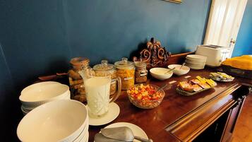 A breakfast buffet with various food items and utensils on a wooden table.