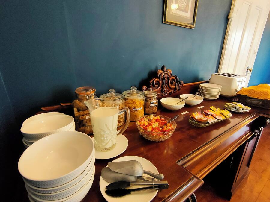 A breakfast buffet with various food items and utensils on a wooden table.