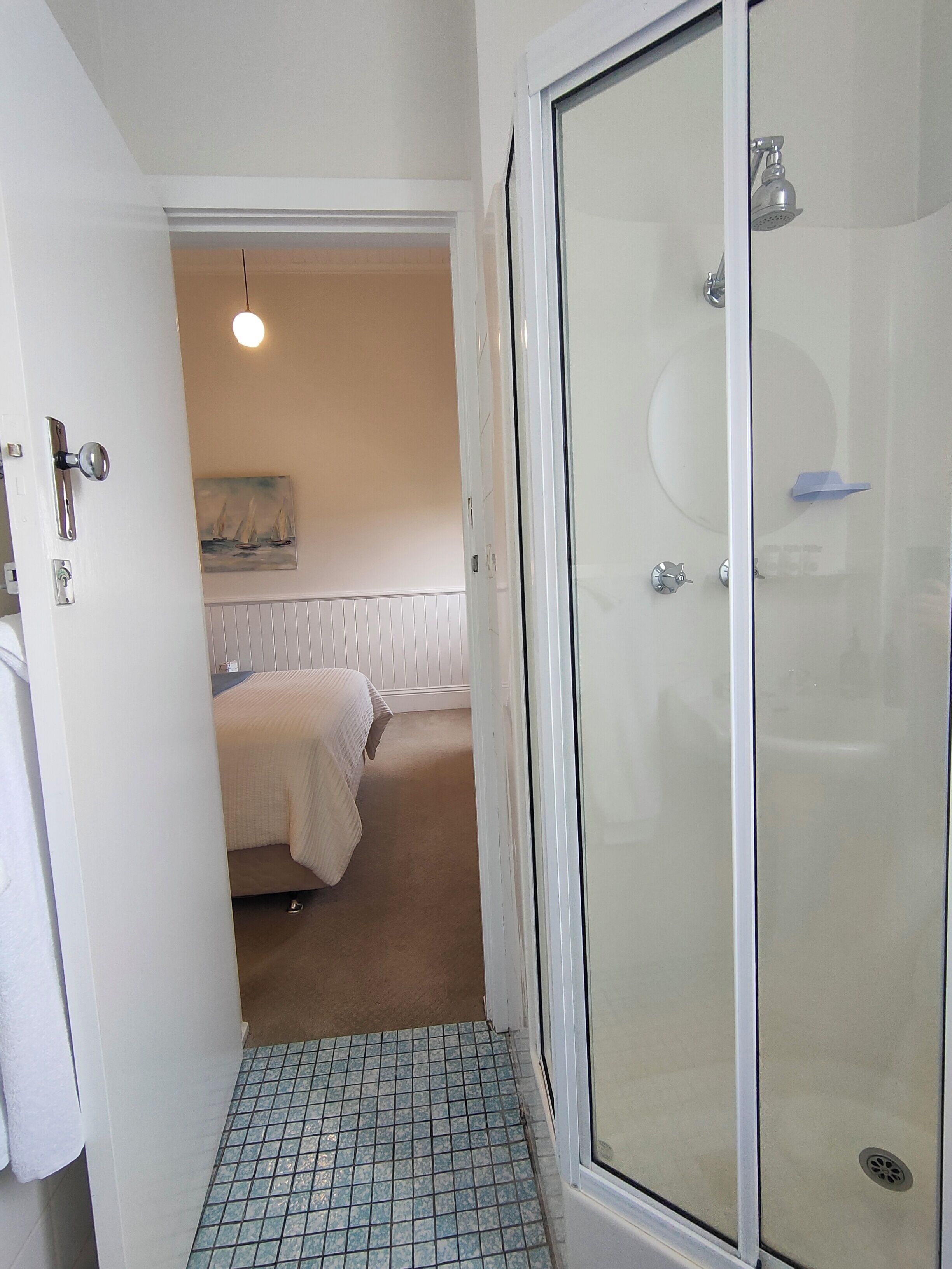Een badkamer met een glazen douchecabine, een wit bad en een klein wastafeltje.