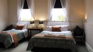 Une chambre double avec deux lits, chacun étant équipé d’un oreiller, d’une table de chevet, d’une lampe et d’une chaise.