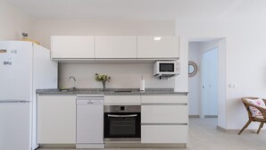 Una cocina moderna con armarios blancos, lavavajillas integrado, horno y microondas.