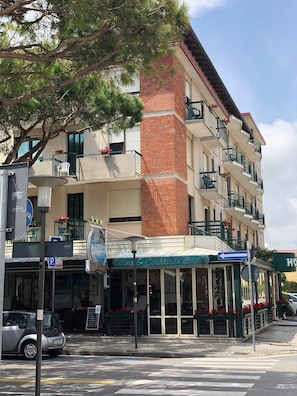Un hotel de diversos pisos amb façana de maó, zona d'seients a l'aire lliure i un restaurant visible anomenat "Wine & Cocktails Bar".