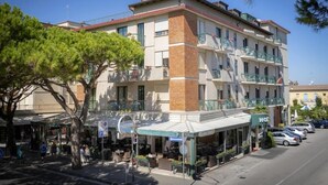 Un hotel de varios pisos con terraza al aire libre, estacionamiento y cielo despejado.