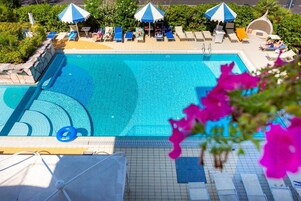 Una piscina con lettini e ombrelloni.