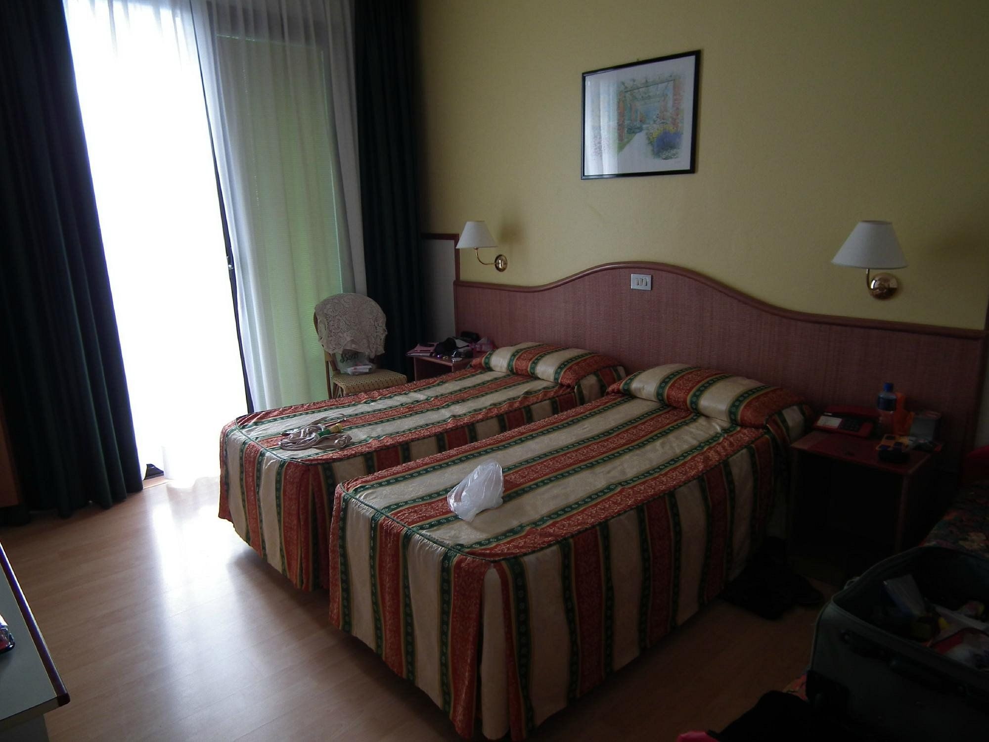 Une chambre d’hôtel avec deux lits, un bureau, une chaise et une fenêtre avec des rideaux.