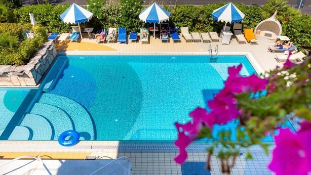 Una piscina con sillas de descanso y sombrillas.
