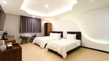 Quarto de hotel com duas camas, uma escrivaninha com cadeira, televisão e uma pequena mesa com bandeja.
