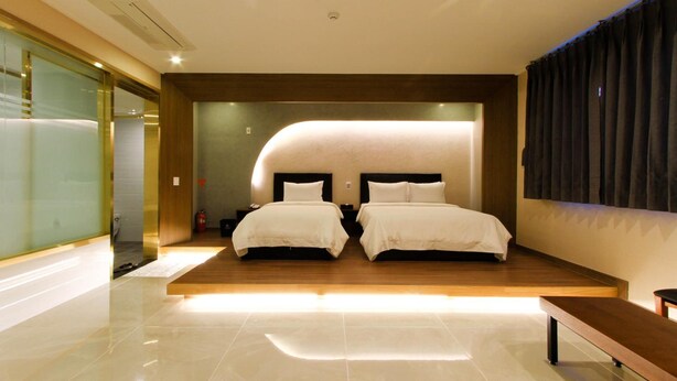 A modern hotel room with a large bed, a bench, and a glass partition. - The King Hotel (Busan)