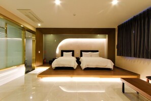 Een moderne hotelkamer met een groot bed, een bank en een glazen scheiding.