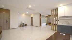A modern, well-lit hotel room with a wooden door, a small table, and a kitchenette area. - The King Hotel (Busan)