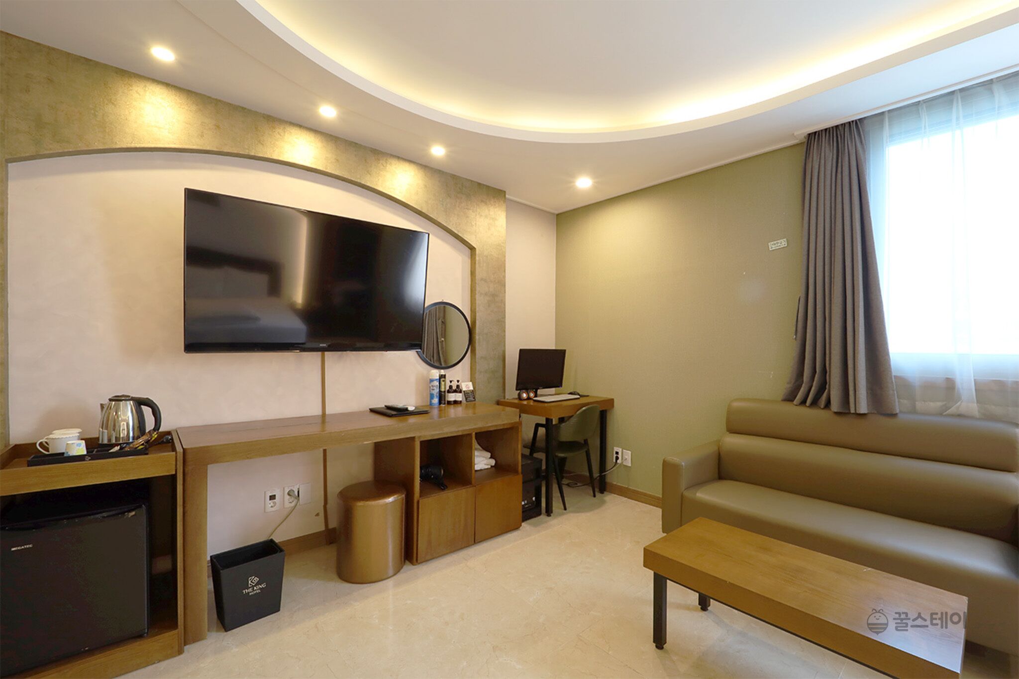A modern living room with a flat-screen TV, a desk with a computer, a sofa, and a coffee table.