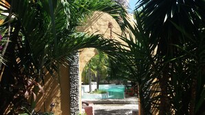 A pathway leading to a pool area surrounded by lush greenery and a stone wall.