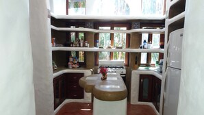 A compact kitchen with a central island, built-in shelves, and a refrigerator.