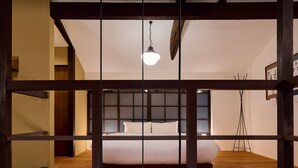 Ein Schlafzimmer mit Holzboden, einem Bett mit weißer Bettwäsche und einer Pendelleuchte.
