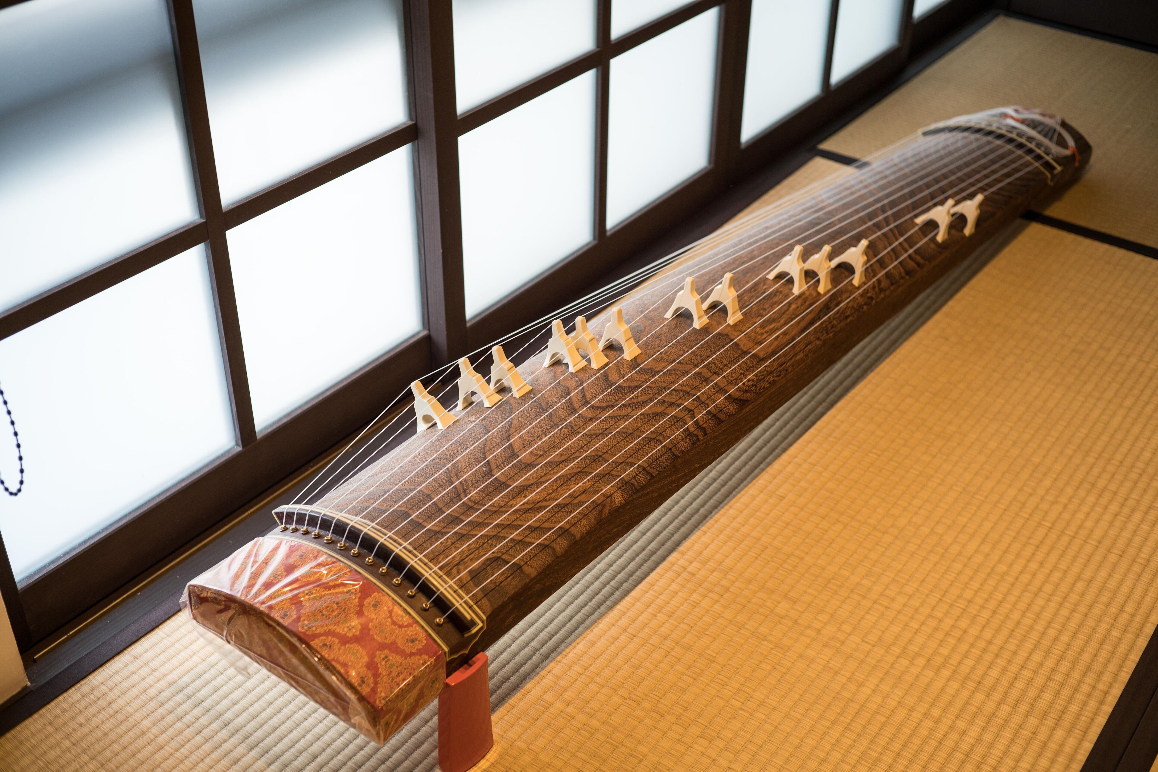 A traditional stringed instrument in a room with tatami flooring and a shoji screen.