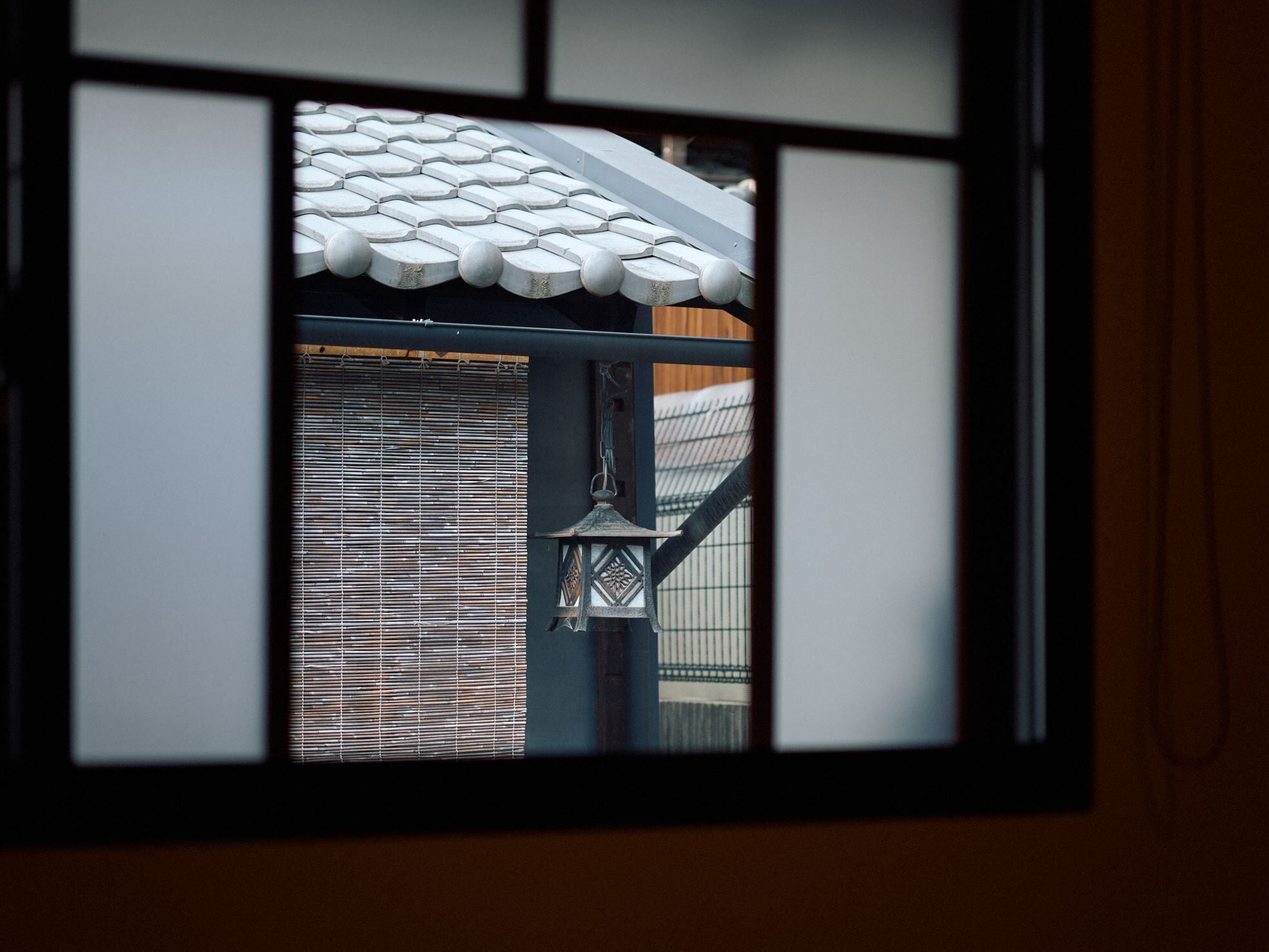 Un tradicional panel japonés shoji con un tejado de baldosas visible a través de la ventana.