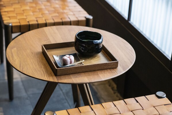 A round wooden table with a black ceramic bowl and a tray containing two cookies.