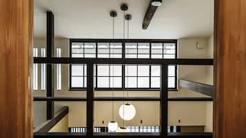 A multi-level interior with wooden beams, large windows, and hanging pendant lights.