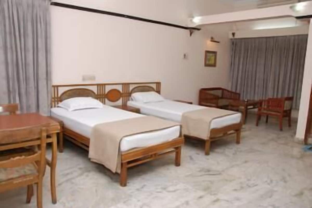 Ein Hotelzimmer mit zwei hölzernen Betten, einem Holztisch und einem Stuhl.