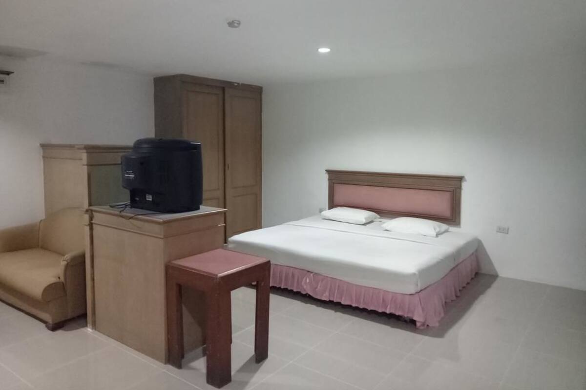 Ein Schlafzimmer mit Bett, kleinem Tisch, Fernseher und Kleiderschrank.