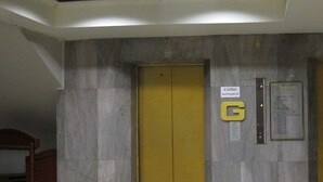 An elevator with a yellow door, a 'G' sign, and a control panel with emergency instructions. - Tongpoon Hotel (Bangkok)