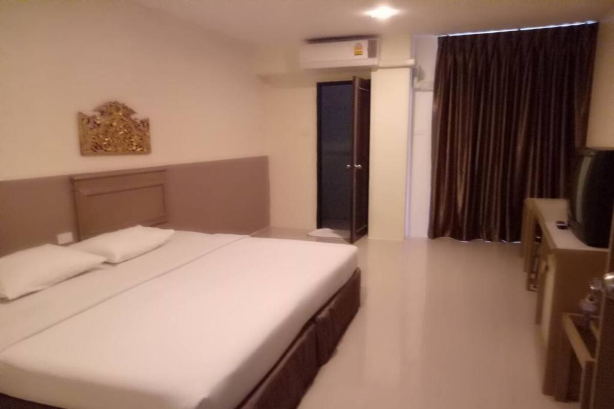 Ein Hotelzimmer mit einem großen Bett, einem Schreibtisch, einem Fernseher und einem Kleiderschrank.