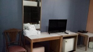 A small room with a wooden desk, a chair, a television, and a small refrigerator. - Tongpoon Hotel (Bangkok)