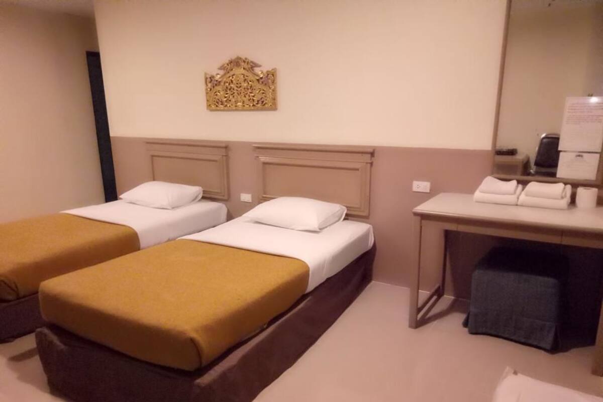 Ein Hotelzimmer mit zwei Betten, einem Schreibtisch mit Computer und einem Spiegel.