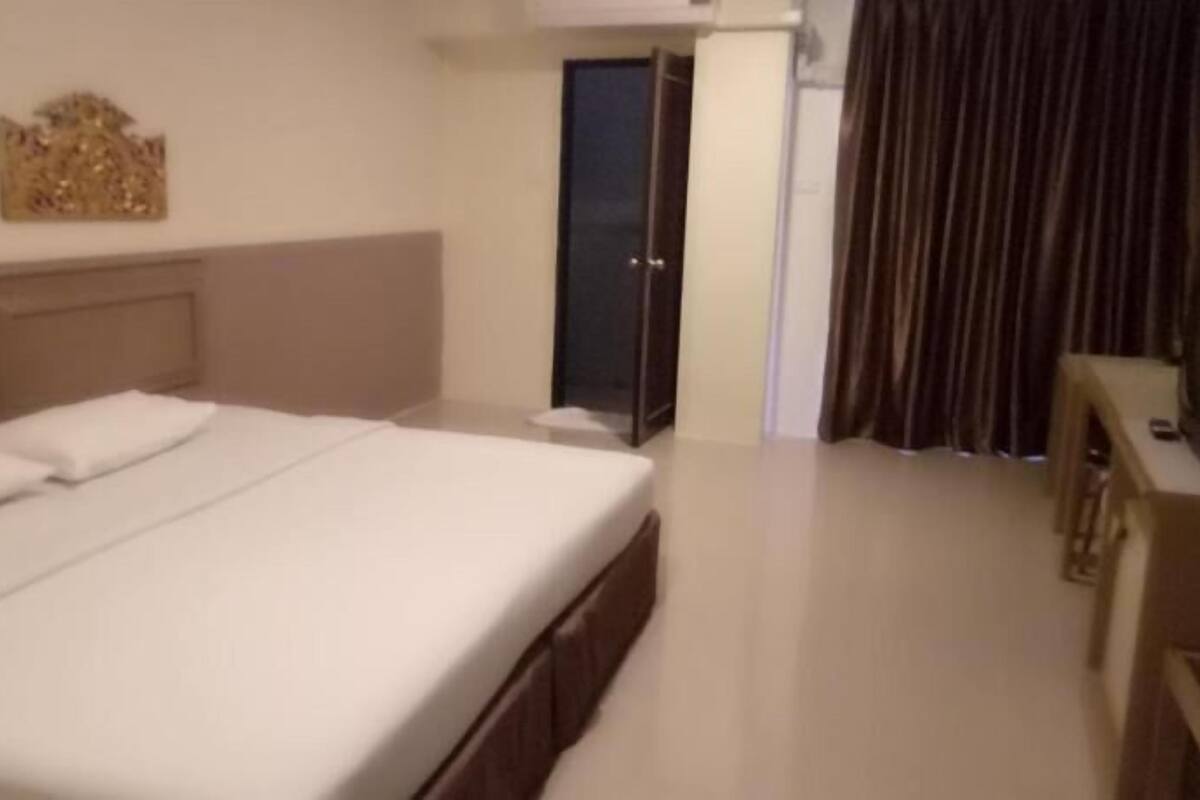 A hotel room with a large bed, a television, a door leading to a balcony, and a wall-mounted artwork.