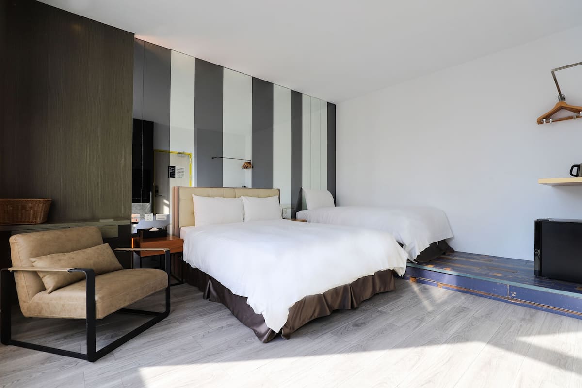 Quarto de hotel moderno com uma cama grande, um sofá, uma escrivaninha e um guarda-roupa.