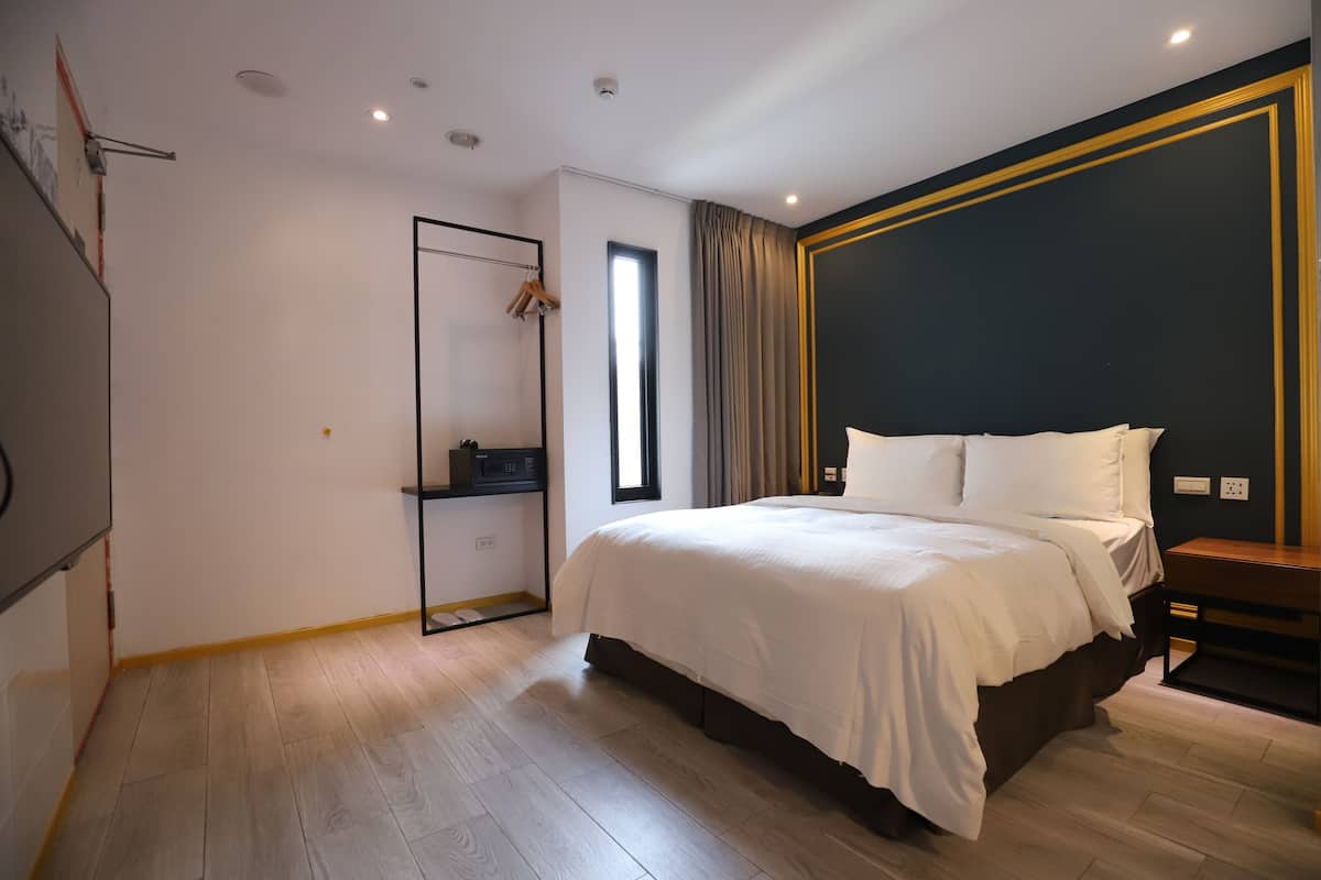 Quarto de hotel moderno com cama grande, guarda-roupa, escrivaninha e janela.