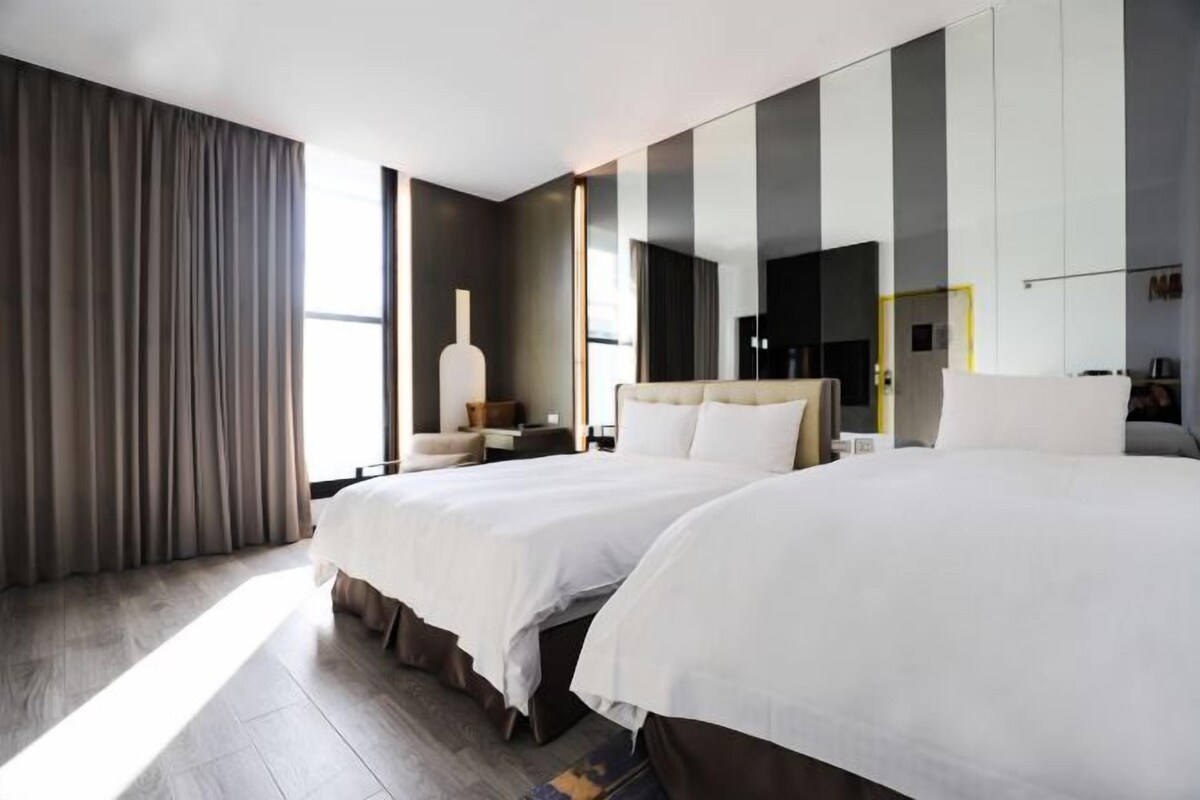 Une chambre d’hôtel moderne avec deux lits, un grand miroir et une vue sur la ville.