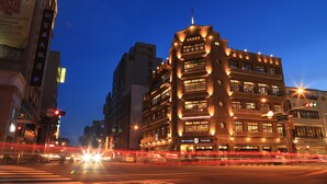 A multi-story building with illuminated signage, likely a hotel or commercial property, featuring a prominent entrance and multiple windows. - Hotel Initial-Beer (Tainan)