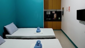 A small, compact room with two beds, a kitchenette, and a TV. - Pete's Inn (Roxas City)