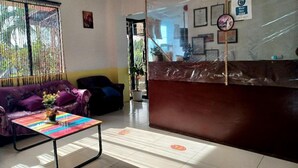 A reception area with a purple sofa, a colorful table, and a reception desk. - Pete's Inn (Roxas City)