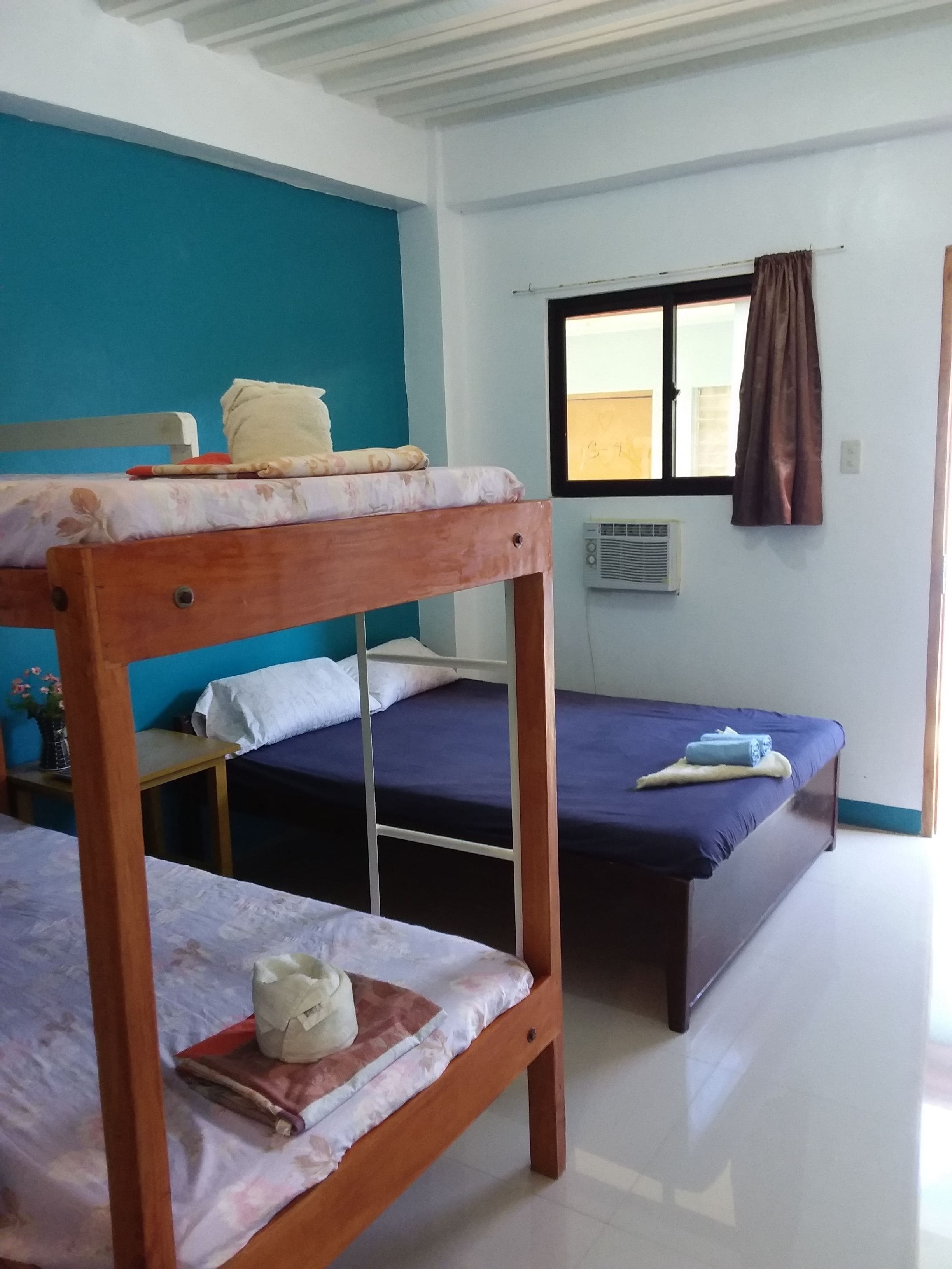 A room with two bunk beds, a window with curtains, and a radiator.