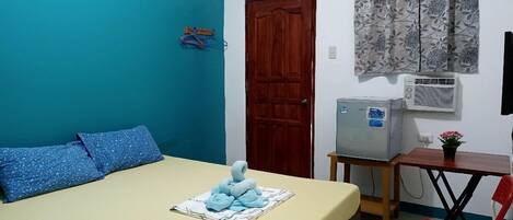 Una habitación con cama, escritorio, silla, aire acondicionado y puerta.