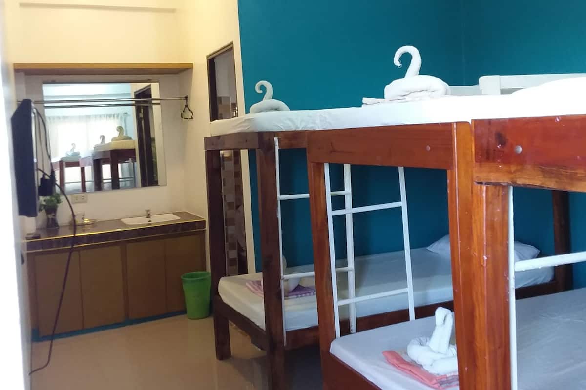 A room with bunk beds, a bathroom with a mirror, and a sink.