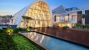Un edificio moderno con un amplio ventanal de vidrio y una zona de piscina.