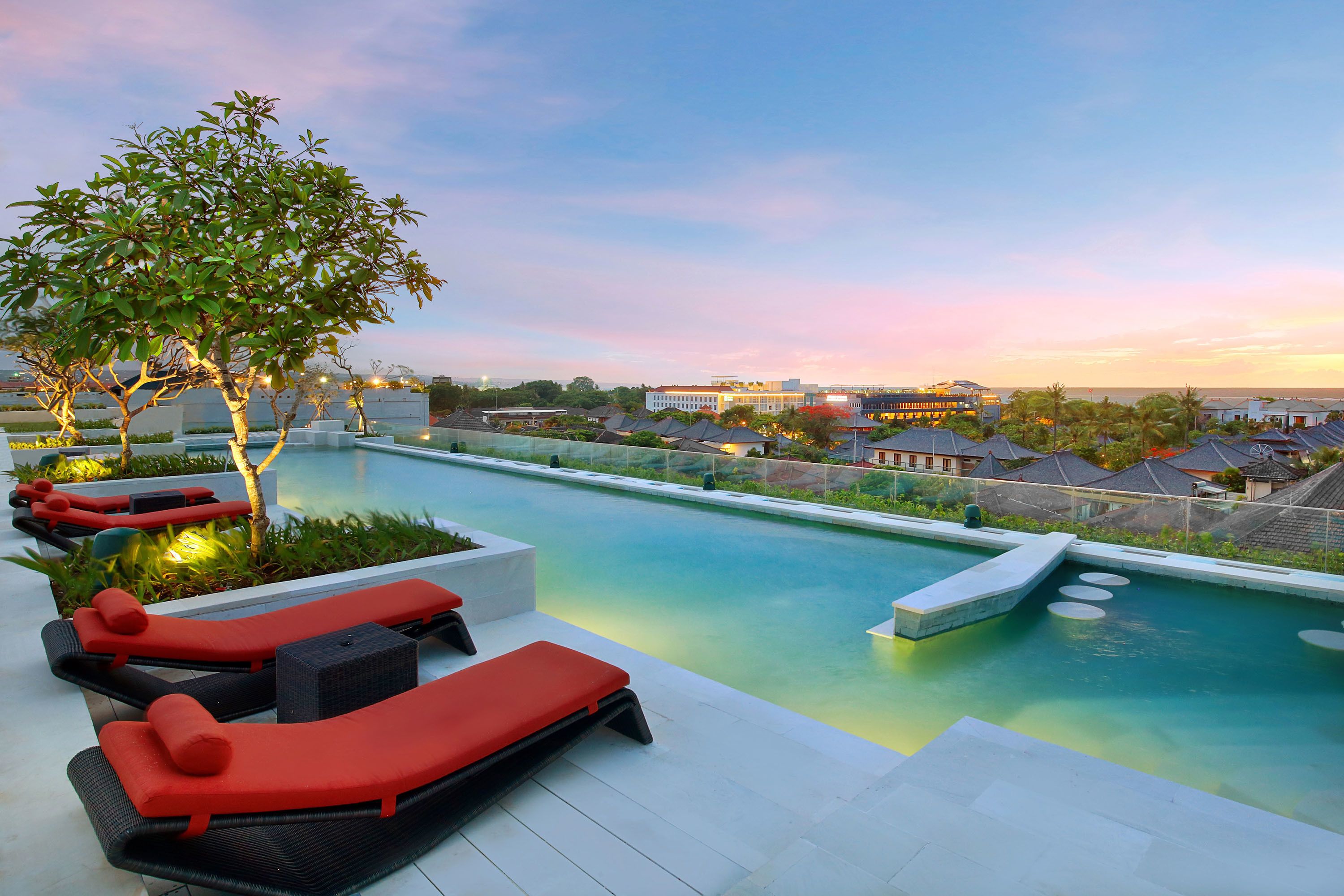 A rooftop pool area with lounge chairs and a tree.