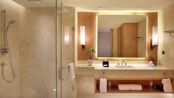 A modern bathroom with a glass-enclosed shower, a large mirror, and a vanity with a sink.