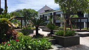 Un patio con plantas en macetas, un pabellón y un edificio de diseño moderno.