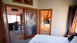 A bedroom with a bed, a bathroom with a shower, and a dining area with a table and chairs. - Kauri House (Wanaka)